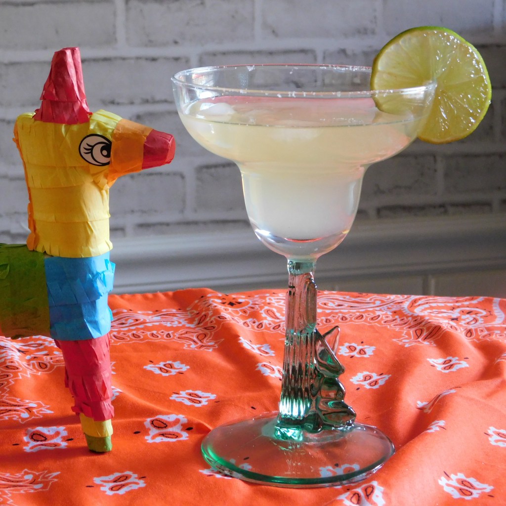 Margarita Mocktail with a colorful donkey piñata examining it. 